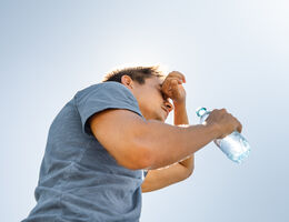 A man with a water bottle wipes his forehead.