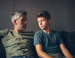 A father and son talk on a couch