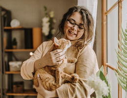 A smiling woman holds a cat.